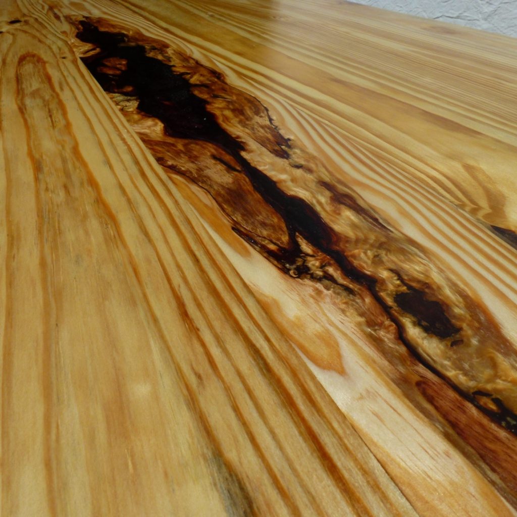 A resin filled void in a heavy reclaimed timber table top.